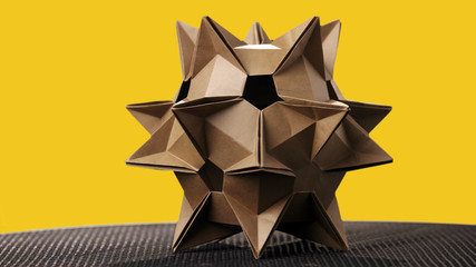 Origami cosmic figure on yellow background. Origami asteroid model on color background. Concept of...