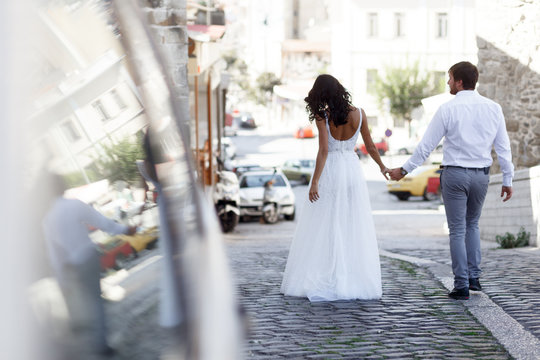 Back view of a romantic couple of a newlyweds walks on the old street greece. Wedding in greece.