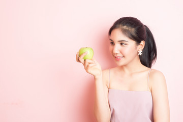 Obraz na płótnie Canvas Healthy girl eating green apple on pink background