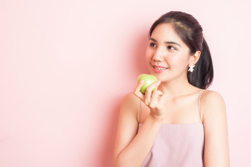 Healthy girl eating green apple on pink  background