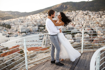 Romantic view of happy couple in white clothes, when they cuddle on green grass. Beautiful...