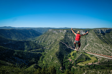 a man walking on the longest slackline ever in Navacelles circus (world humanity patrimony) at 300...