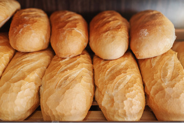 Close up of fresh delicious loafs of bread in row on shelves ready for sale. Bakery interior.