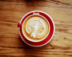 Top view of fresh delicious cup of coffee with cream on desk in cafeteria.