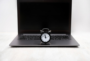 Black alarm clock on laptop. concept work time to be in computer. business schedule concept with...