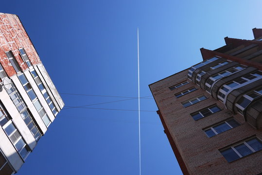 The track of the plane in the sky. Blue sky and high-rise buildings flying plane at high altitude. Details and close-up.