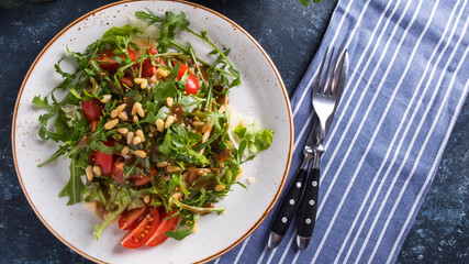 Arugula with pine nuts, tomatoes and cheese. Healthy fresh salad with arugula. Top view. Copy space