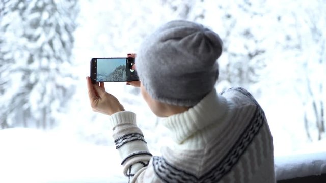 Young woman uses a smartphone to video a beautiful view in the mountains, rear view