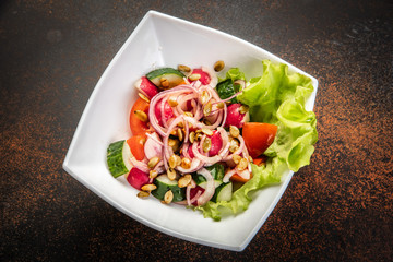 Fresh salad with mixed greens in bowl on wooden background.