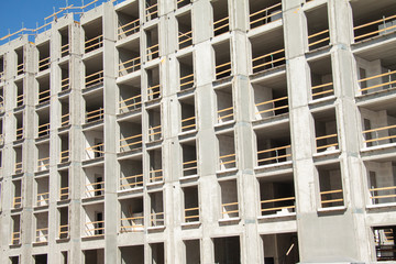 Construction work site of a multi-storey building showing frames of naked concrete walls with empty spaces. Contruction workes protected by wooden security boards. Closeup image.