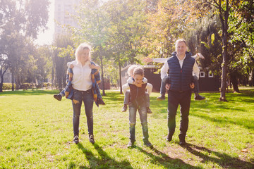 Fototapeta premium Theme family active leisure outside in nature. large Caucasian family with four children. Mom and Dad actively relaxing. enjoy life in park near house on grass. Children on back shoulders roll on top