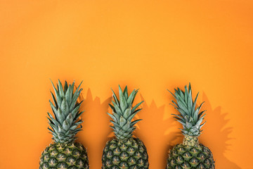 top view of pineapples on orange background with copy space