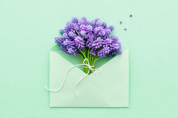 Fototapeta premium Spring lilac flowers in a turquoise envelope for Mother's day flat lay