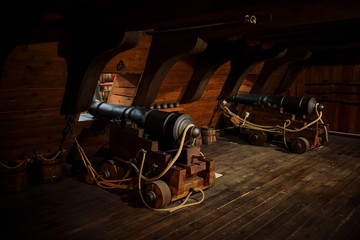 interior view of Cannons At The Deck and Cannon Balls plus windows on old galleon with ropes.