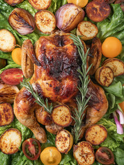 Roasted chicken with grilled potatoes and onion, fresh green salad on wooden table from above. Owen cooked meat with vegetables. Original food serving in restaurant, cafe. Holiday dinner. 