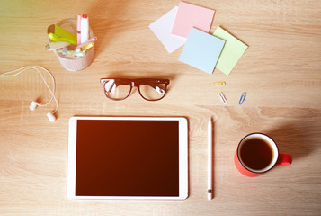 Wooden Desk. White tablet with black-rimmed glasses. Cup of tea.