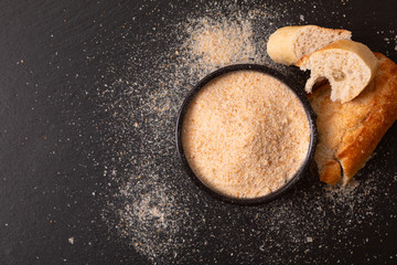 Food ingredients homemade organic bread crumbs in black ceramic bowl on black slate board