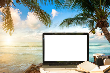 Mockup image of laptop with empty screen with camera,notebook,coffee cup on table with at landscape early morning sunrise over the sea,working on the beach,Freelance work and traveler concept.