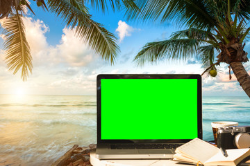Mockup image of laptop with empty screen with camera,notebook,coffee cup on table with at landscape early morning sunrise over the sea,working on the beach,Freelance work and traveler concept.