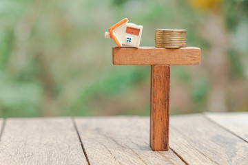 home and coins balancing on wooden. Property investment and house mortgage financial real estate concept.  Saving money for buy a new house or real estate and loan for plan business investment concept