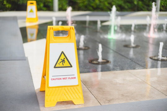Caution wet floor sign on wet tiles floor at outdoor walkway