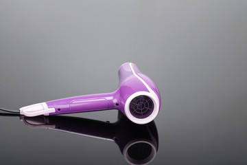 Pink hair dryer on the grey mirror background with copy space