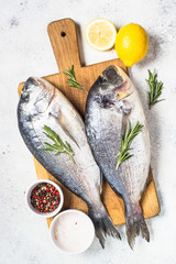 Raw dorado fish on cutting board on the table.