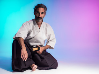 bearded man practicing aikido illuminated with colorful gels in studio photo with blue and pink...