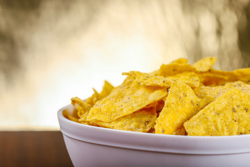 Yellow nacho in white bowl on the wooden table