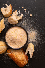 Food ingredients homemade organic bread crumbs in black ceramic bowl on black slate board