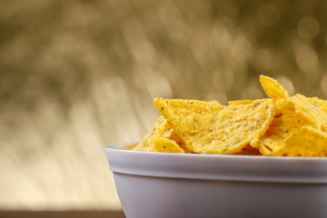 Yellow nacho in white bowl on the wooden table