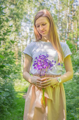 Young woman with a bouquet of wild flowers in summer in a park