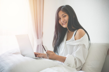 Obraz premium Young woman working on a laptop and uses credit card, bussiness and shopping concept