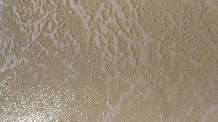 Soft Ocean Waves on the White Sand Tropical Beach Closeup. Sea Foam Washes over the Sand. Sea Waves. Serene Relaxation Scene. Sunny Destination Vacation Background.