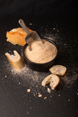 Food ingredients homemade organic bread crumbs in black ceramic bowl on black slate board