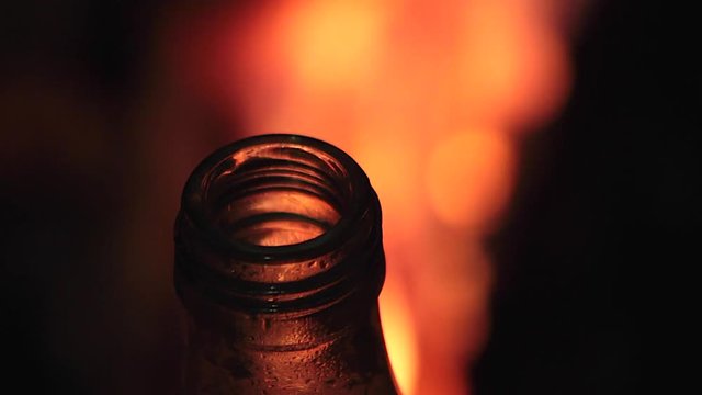 Boca de botella de refresco con fondo de fuego borroso