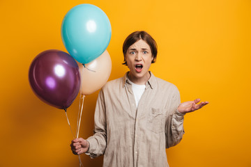 Shocked handsome man in shirt holding balloons