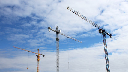 Construction site tower cranes against blue sky