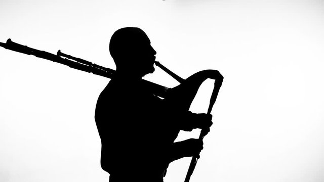 black silhouette on white background man playing bagpipes, national ethnic instrument close up