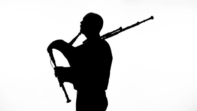 black silhouette on white background man playing bagpipes, national ethnic instrument close up