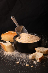 Food ingredients homemade organic bread crumbs in black ceramic bowl on black slate board