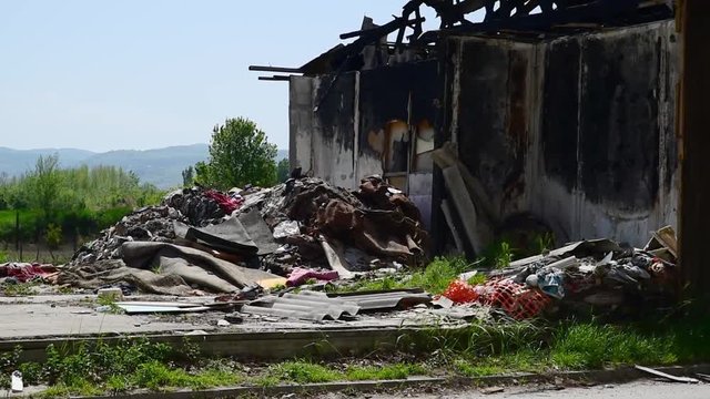 Damaged house in fire, Burnt abandoned wooden barrack with pile of garbage and litter and burned walls 