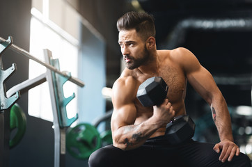 Fototapeta na wymiar Strong muscular man doing exercises with dumbbells