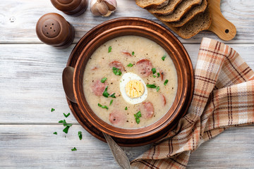 Traditional polish soup Zurek in ceramic bowl on wooden table. Top view.