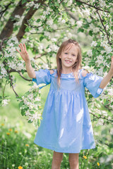 Adorable little girl in blooming apple garden on beautiful spring day