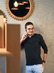 Young man working with phone and computer, receiving phone call, talking with partners 