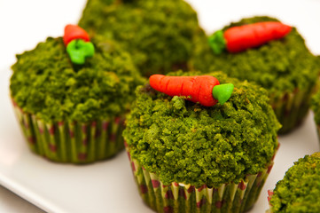 Green spinach cupcakes with candy carrots topping.
