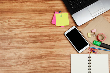 Smartphone and office supplies on wooden table, top view