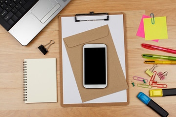 Smartphone and office supplies on wooden table, top view