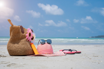 Straw bag, straw hat, sunblock, sandals and sun glasses on beach - Image